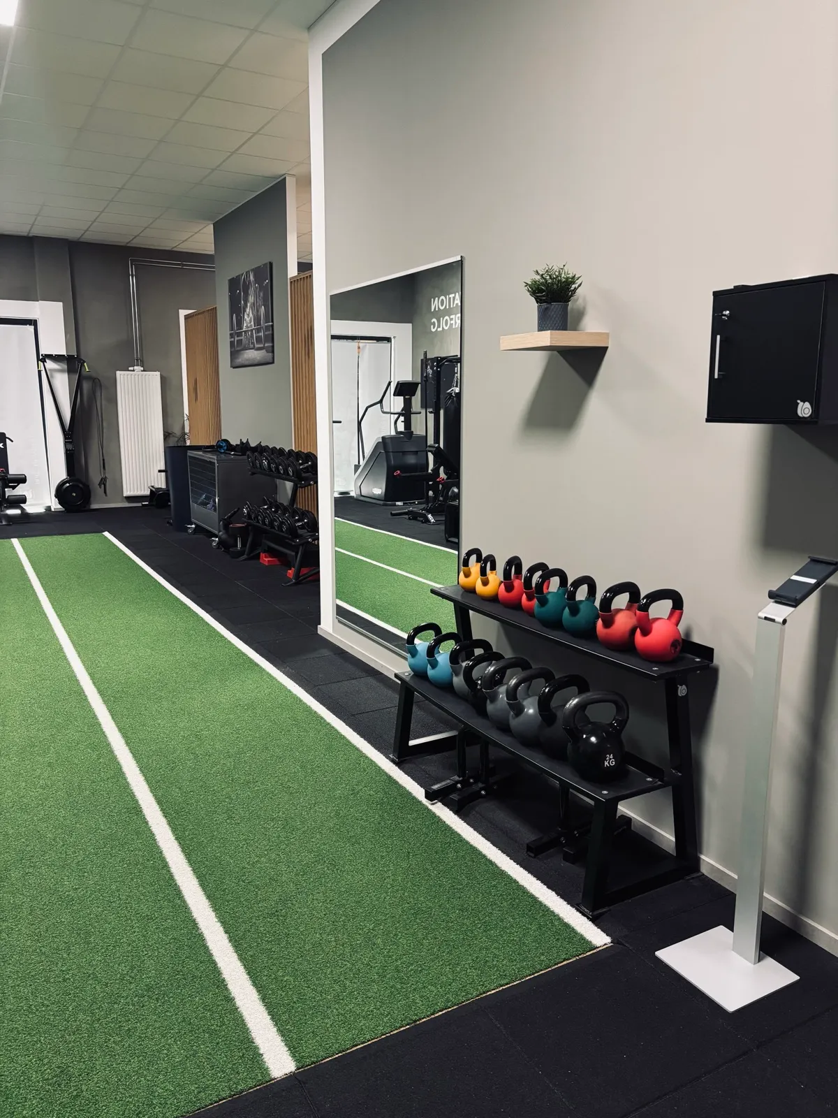 Kunstrasenbahn mit Kettlebells, Hanteln und Spiegelwand